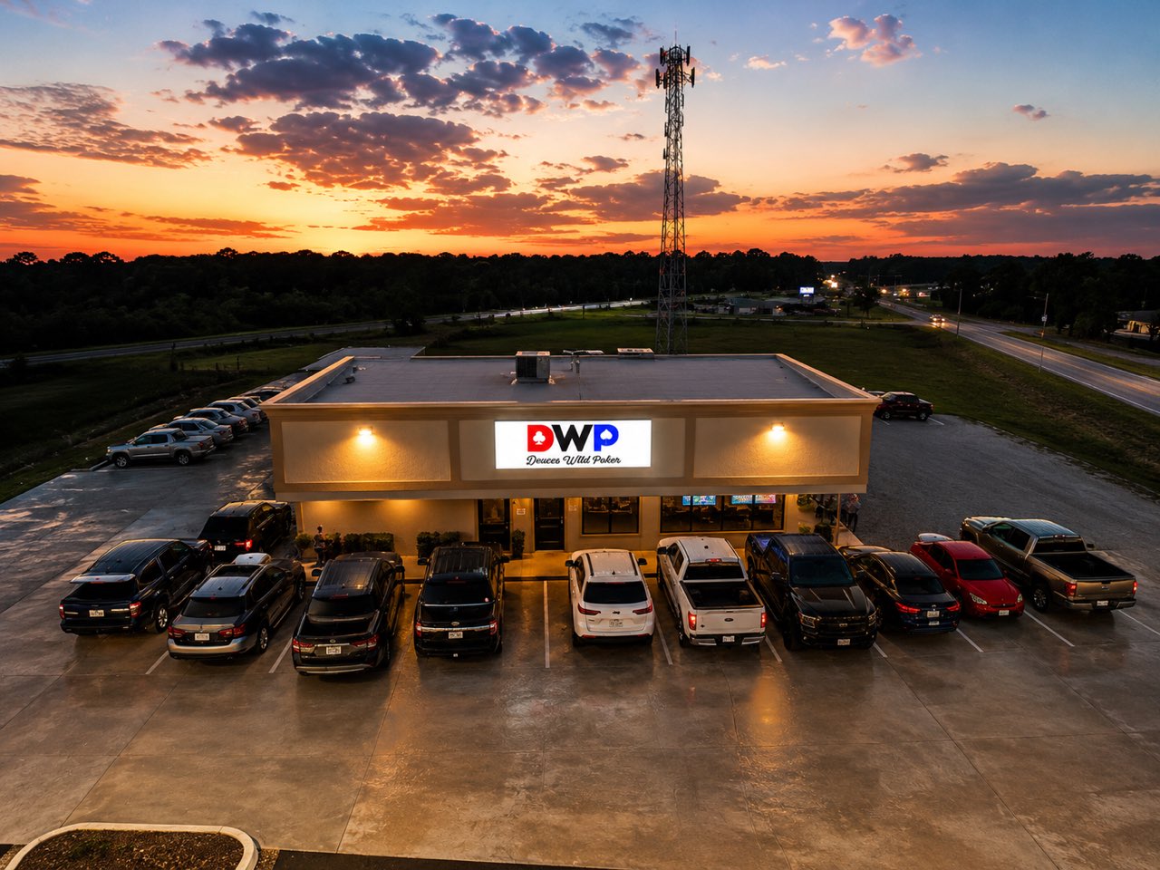 Deuces Wild Poker Club at sunset — the lit DWP sign and free parking lot at 120 FM 2821 Rd E, Huntsville, TX
