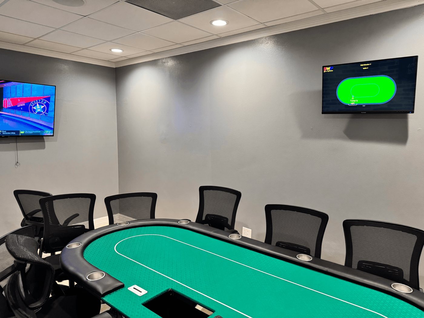 The private poker room at Deuces Wild with a full table and screens